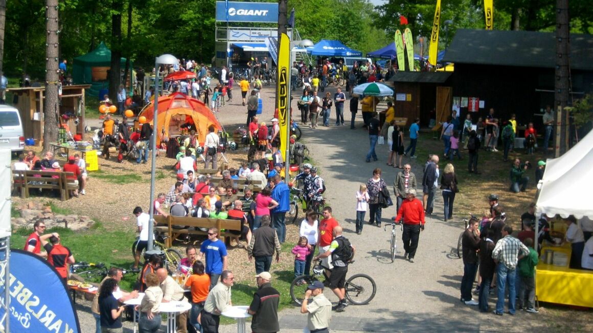Zahlreiche Besucher und Fahrradfahrer tümmeln sich auf einem Markt in der freien Natur bei gutem Wetter